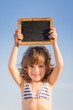 Happy child holding blank blackboard