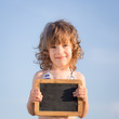 Happy child holding blank blackboard