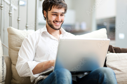 Photo: Young man relaxing on the sofa with a laptop Young man relaxing on the sofa with a laptop