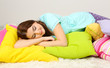 Beautiful young girl with pillows in room