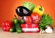 Fresh vegetables in scales on table on orange background