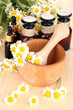 Essential oil and chamomile flowers in mortar on wooden table