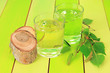 Glasses of birch sap on green wooden table