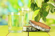 Glasses of birch sap on wooden table, on green background