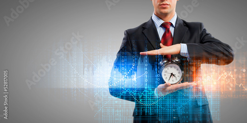 Photo: Business man holding alarmclock Business man holding alarmclock