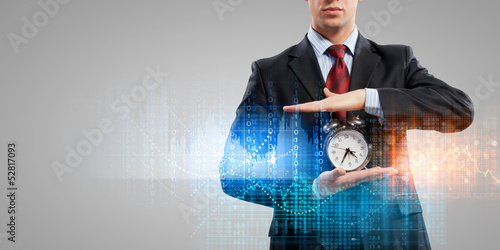 Photo: Business man holding alarmclock Business man holding alarmclock