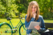 Pensive teenager in park with tablet