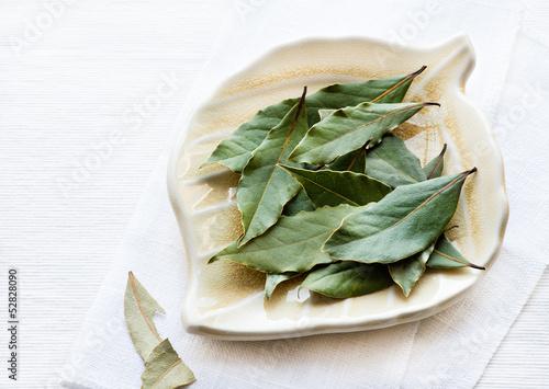 Photo: Bay leaves on plate over light background Bay leaves on plate over light background