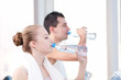 Man and woman drinking water after sports in gym