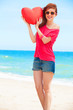 Redhead teen girl with heart shape on the beach