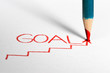 Pastel pencil writing word GOAL on paper.