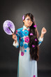 Beautiful asian woman wears a national dress is holding a fan