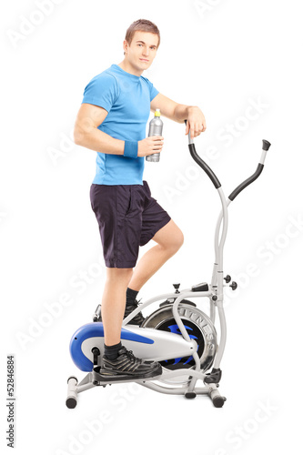 Photo: Young man posing on a cross trainer fitness machine Young man posing on a cross trainer fitness machine