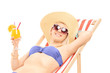 Smiling young woman sunbathing and holding a cocktail