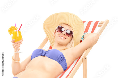 Photo: Smiling young woman sunbathing and holding a cocktail Smiling young woman sunbathing and holding a cocktail