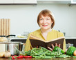  mature woman cooking  with  cookery book