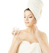 Photo: Spa woman, wrapped in towel applying skin care cream Spa woman, wrapped in towel applying skin care cream