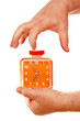 orange alarm clock in a hand on a white background.