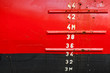 Red ship hull with waterline and draft scale measure