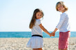 Two friends holding hands on beach.
