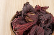 Dry hibiscus tea flowers in wooden bowl close up