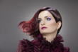 Woman with striking makeup and extravagant hairstyle in studio.
