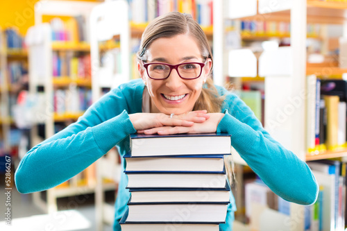 Photo: Student with pile of books learning in library Student with pile of books learning in library