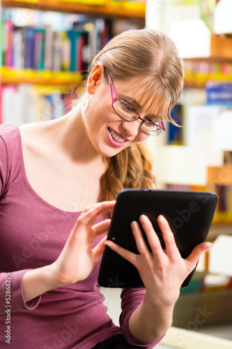 Photo: student in library learning with tablet computer student in library learning with tablet computer