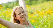 woman arms stretched high in meadow of yellow flowers