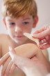 Mom putting adhesive bandage on boy