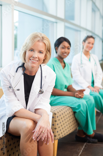 Photo: smiling female doctor sitting with smiling female nurses smiling female doctor sitting with smiling female nurses