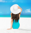 model sitting in swimsuit with hat
