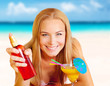 Woman with cocktail and sunblock on the beach
