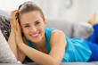 Photo: Smiling young woman laying on sofa in living room Smiling young woman laying on sofa in living room