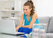 Photo: Happy young woman with laptop in living room Happy young woman with laptop in living room