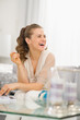 Photo: Smiling young housewife sitting on divan in living room Smiling young housewife sitting on divan in living room