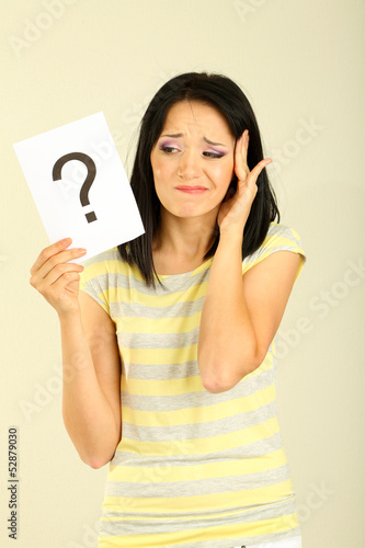 Photo: Woman with question marks on grey background Woman with question marks on grey background