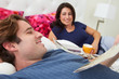 Couple Relaxing In Bed With Coffee And Newspaper