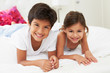 Children Lying On Bed In Pajamas Together
