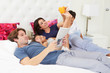 Family Relaxing In Bed With Coffee And Newspaper