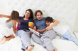 Family Relaxing In Bed With Coffee And Newspaper