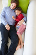 Overhead View Of Father And Daughter Relaxing On Sofa