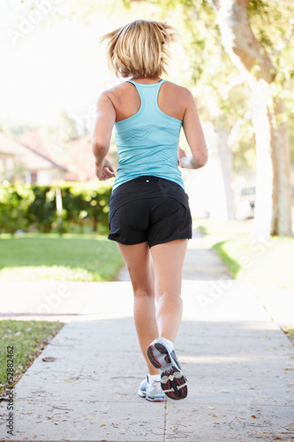 Photo: Rear View Of Female Runner Exercising On Suburban Street Rear View Of Female Runner Exercising On Suburban Street