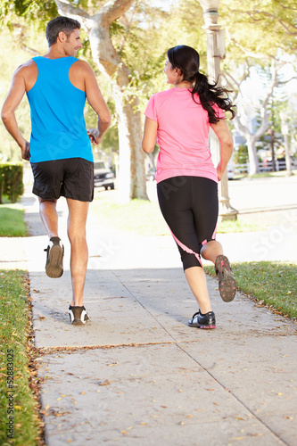 Photo: Rear View Of Couple Running On Suburban Street Rear View Of Couple Running On Suburban Street