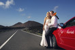 Newlyweds on the road next to the car "Just Married".