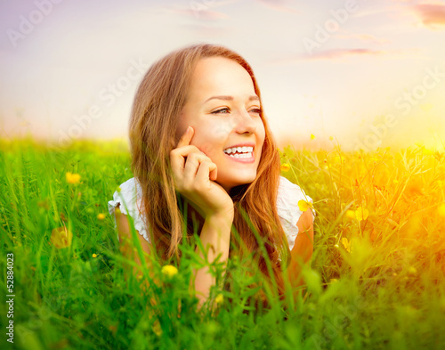 Photo: Beauty Girl in the Meadow lying on Green Grass Beauty Girl in the Meadow lying on Green Grass
