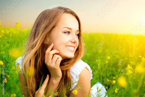 Photo: Beauty Girl in the Meadow lying on Green Grass with wild Flowers Beauty Girl in the Meadow lying on Green Grass with wild Flowers