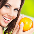 Foto: Young woman with orange, outdoors Young woman with orange, outdoors
