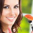 Foto: Smiling young woman eating tomato, outdoors Smiling young woman eating tomato, outdoors