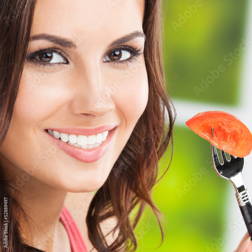Photo: Smiling young woman eating tomato, outdoors Smiling young woman eating tomato, outdoors